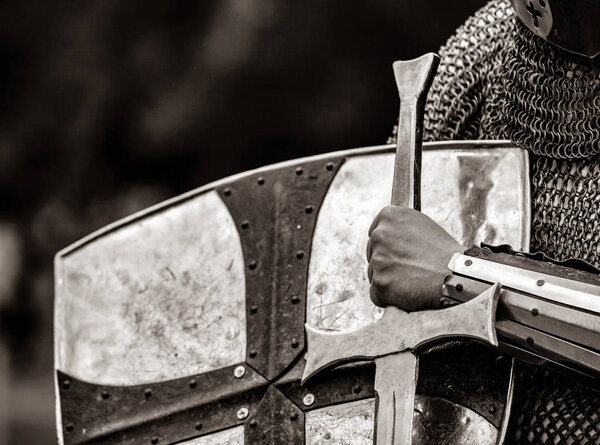 Closeup view on traditional medieval knight with shield and sword. Image in black and white color style