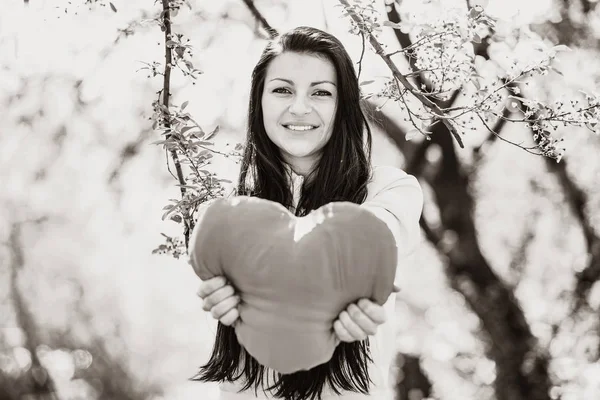 Girl with heart shape in spring blooming garden — Stock Photo, Image