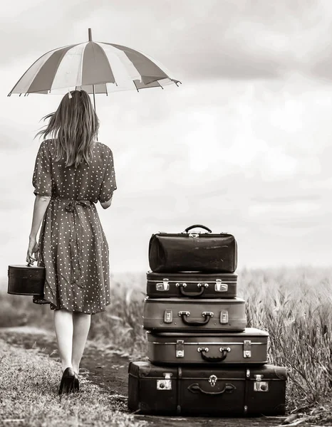 Dziewczyna z walizki i parasol na wiejskiej drodze podczas podróży — Zdjęcie stockowe