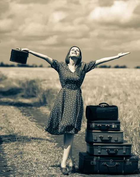 Girl with suitcases on rural road — Stock Photo, Image