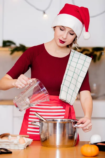 Ama de casa en Santa Claus sombrero cocina cena de Navidad —  Fotos de Stock