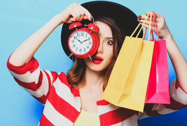 Woman with alarm clock and shopping bags — Stock Photo, Image