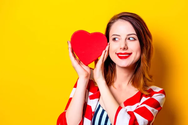 Mujer con caja en forma de corazón sobre fondo amarillo — Foto de Stock