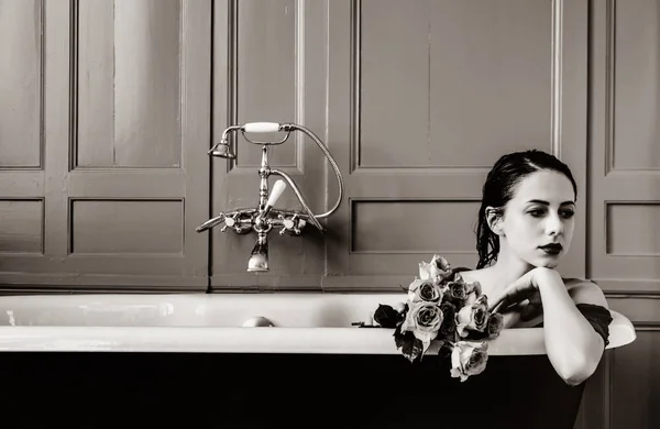 Jovem mulher em banho com flores — Fotografia de Stock