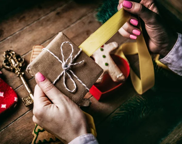 Mains enveloppant cadeaux de Noël et biscuits — Photo