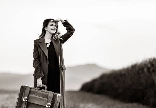 Женщина в деревне с чемоданом — стоковое фото