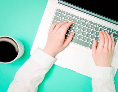Female hands with cup of coffee and laptop