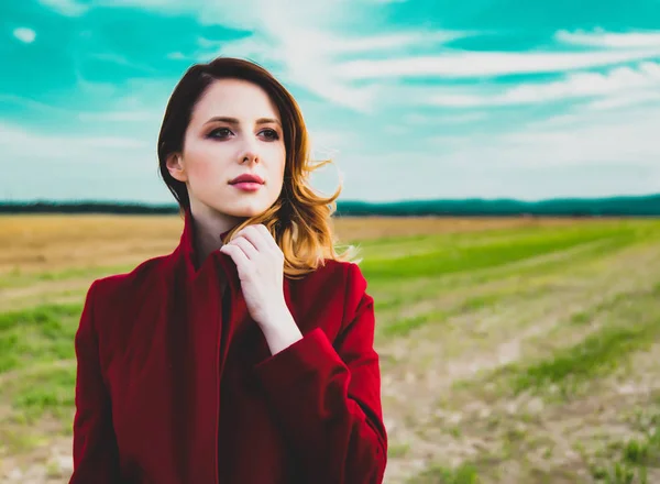 Žena v červeném kabátě na venkově field — Stock fotografie