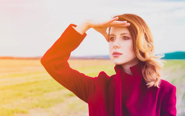 Vrouw in rode jas op platteland field — Stockfoto