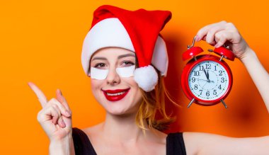 Santa Claus şapka ile çalar saat izole arka plan üzerinde onun gözünde için göz bandı kullanan kadın. Genelde oldukları gibi doğal ve gerçek erkek portresi gibi görünüyor