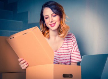 kutuları ve merdivenlerde evde oturan dizüstü hareket ile genç Kızıl saçlı kadın. Avrupa etnik köken