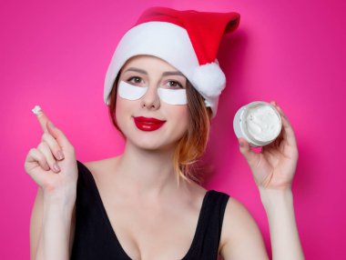 Santa Claus şapka izole pembe arka plan üzerine krema ile onun gözünde için göz bandı kullanan kadın. Genelde oldukları gibi doğal ve gerçek erkek portresi gibi görünüyor