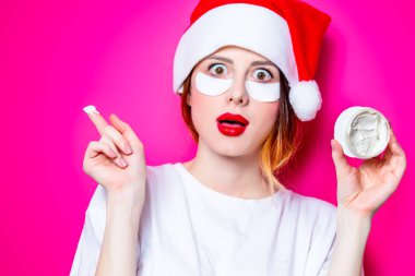 Santa Claus şapka izole pembe arka plan üzerine krema ile onun gözünde için göz bandı kullanan kadın. Genelde oldukları gibi doğal ve gerçek erkek portresi gibi görünüyor