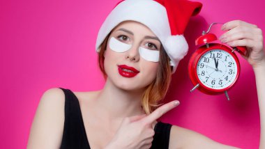 Santa Claus şapka ile çalar saat izole pembe arka plan üzerinde onun gözünde için göz bandı kullanan kadın. Genelde oldukları gibi doğal ve gerçek erkek portresi gibi görünüyor