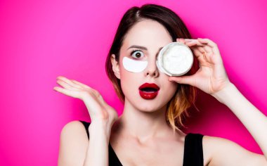 Onun gözleri ve izole pembe arka plan üzerinde krem göz bandı kullanan kadın. Genelde oldukları gibi doğal ve gerçek erkek portresi gibi görünüyor