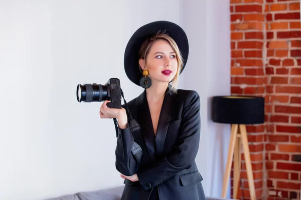 Meisje in een zwarte jurk en muts met camera — Stockfoto