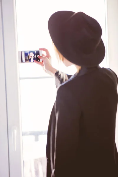 Ung flicka i svart gör en selfie — Stockfoto