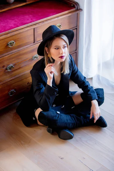 Дівчина в чорному капелюсі і сукня сидить на підлозі . — стокове фото