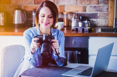 Güzel genç fotoğrafçı fotoğraf makinesi ile mutfak oturma
