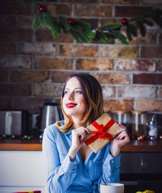 Güzel genç kadın oturma ve mutfak mevcut hediyeler ile at. Noel zamanı 