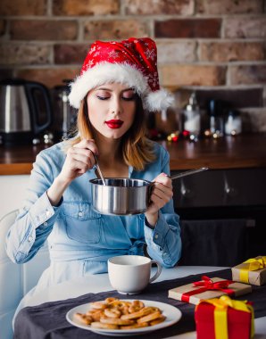 Mutfak pan ve kaşık mevcut hediyeler etrafında oturan güzel ve genç birbayan. Noel zamanı
