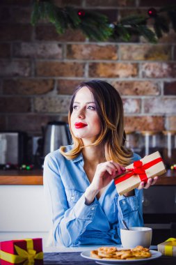 Güzel genç kadın oturma ve mutfak mevcut hediyeler ile at. Noel zamanı 