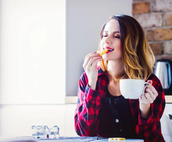 お茶やコーヒー赤シャツのキッチンで座っていると若い女性の肖像画 朝の時間 — ストック写真