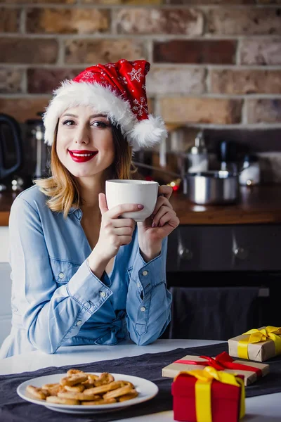 贈り物でキッチンに座って美しい若い女性 クリスマスの時期 — ストック写真