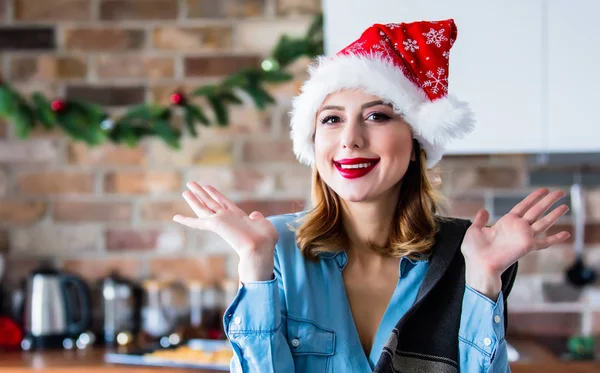 キッチンでサンタ クロースの帽子の美しい若い女性 クリスマスの時期 — ストック写真