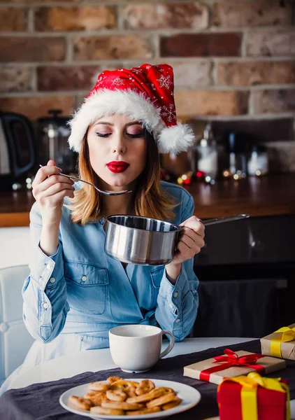 パンと贈り物の周りスプーン キッチンで座っている美しい若い女性 クリスマスの時期 — ストック写真