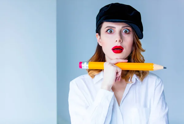 Giovane donna rossa in cappello in possesso di chuge matita — Foto Stock