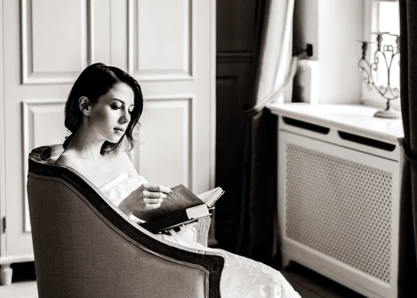 Junge rothaarige Frau sitzt im Stuhl und liest Buch. — Stockfoto