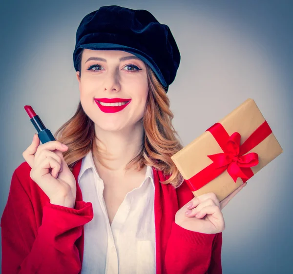 Donna in cardigan rosso e cappello con rossetto e confezione regalo — Foto Stock