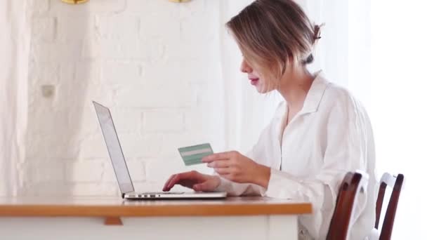 Menina com computador portátil segurando um cartão de crédito . — Vídeo de Stock