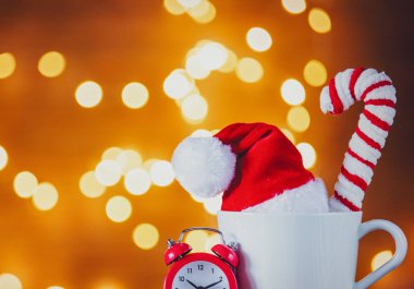 Beyaz fincan çay veya kahve ve arka plan üzerinde Noel ışıkları çalar saat