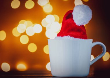 Beyaz fincan çay veya kahve ve Noel ışıkları arka plan üzerinde