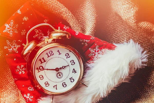 ジュートの背景にクリスマス サンタ クロースの帽子とビンテージ目覚まし時計 — ストック写真