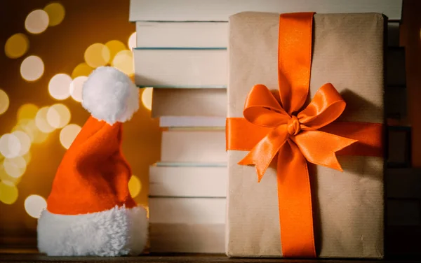 Weihnachtsgeschenkschachtel Weihnachtsmann Hut Und Bücherstapel Mit Lichterketten Auf Dem Hintergrund — Stockfoto