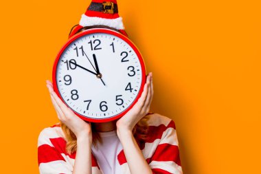 Kadın sarı arka plan üzerinde büyük saat ile gizleme