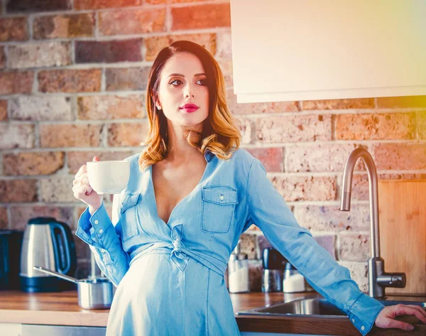 Беременная женщина в синем платье с чашкой кофе или чая — стоковое фото