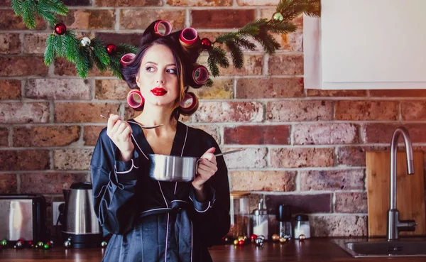 Pregnant housewife in bathrobe cooking at kitchen in Christmas time — Stock Photo, Image