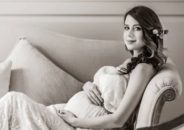 Giovane donna incinta in abito bianco seduta — Foto Stock