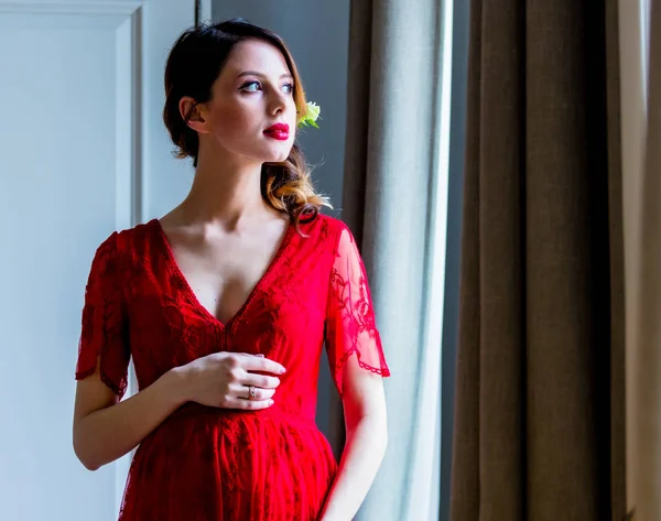Jonge vrouw met rode jurk tegoed op kamer — Stockfoto