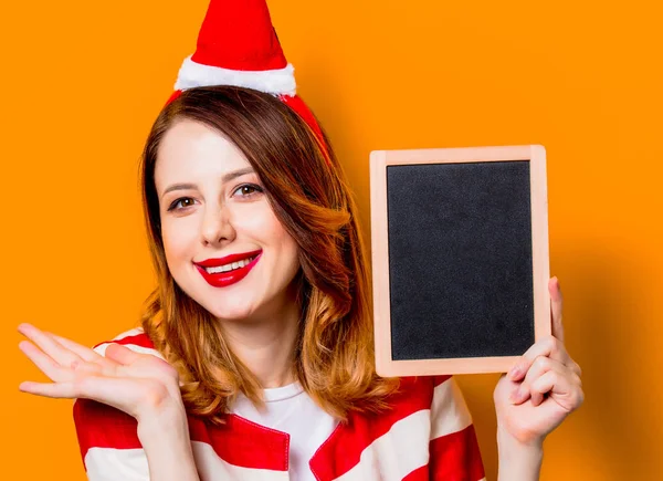 Mulher em chapéu de Papai Noel com quadro negro — Fotografia de Stock