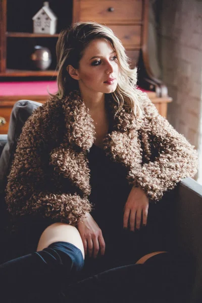 Дівчина з макіяжем в пальто, сидячи на підлозі вдома — стокове фото