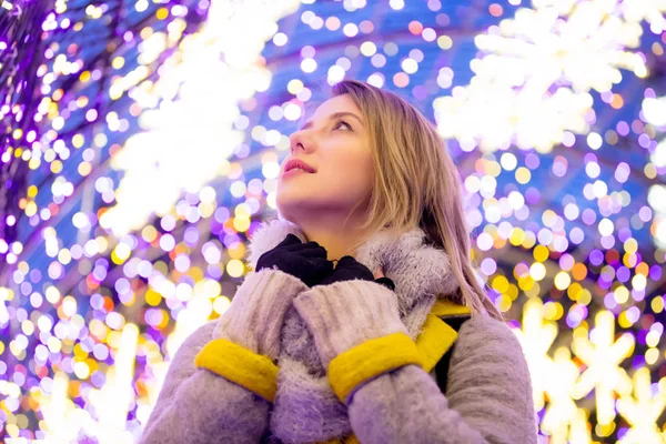 Mulher de casaco e cachecol com luz do tempo de Natal — Fotografia de Stock