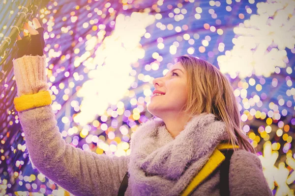 Mulher de casaco e cachecol com luz do tempo de Natal — Fotografia de Stock