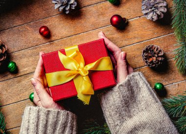 Noel hediye kutusu ahşap masa üzerinde tutan eller