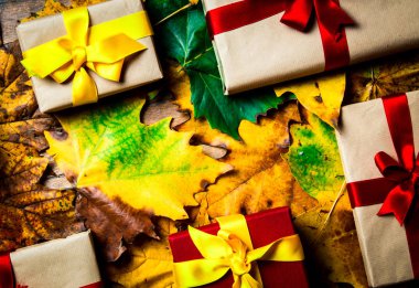 Hediye kutuları ahşap arka plan üzerinde akçaağaç yaprakları üzerinde