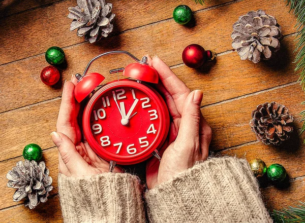 Manos femeninas sosteniendo reloj despertador clásico de Navidad — Foto de Stock